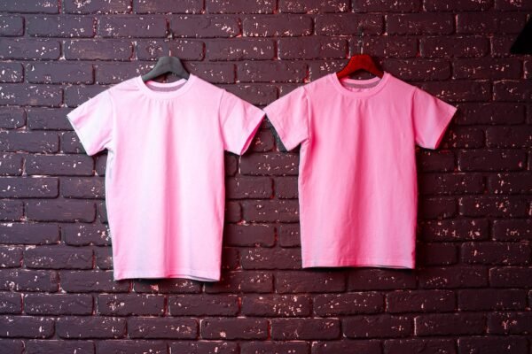 White t-shirt hanging on hanger against brick wall, copy space